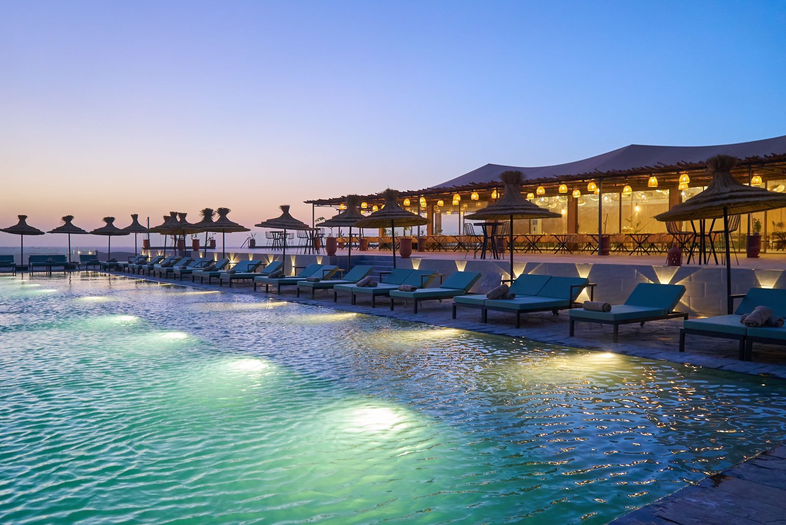 Camp lit at blue hour beside the pool in the Agafay Desert near Marrakech