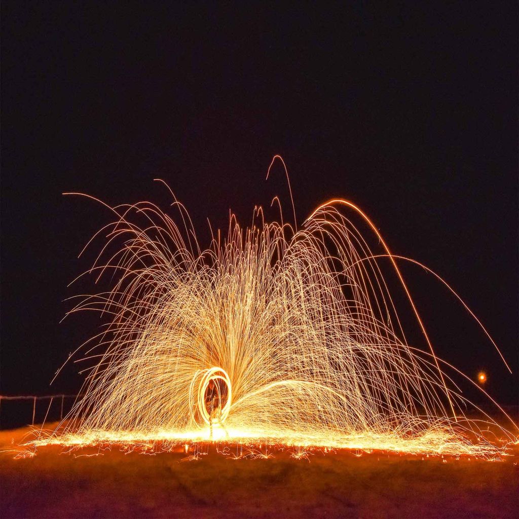 Fire show at night in the Agafay Desert, sparks arcing out in a circle against the dark