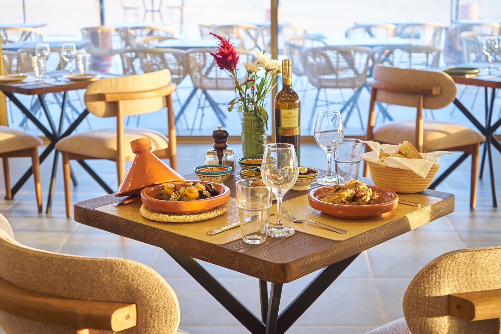Table laid for lunch with a tagine, Moroccan salads and bread, the desert visible outside