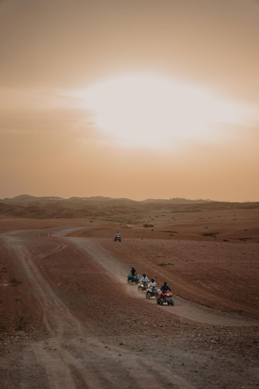 Quad bikes riding in single file along a desert track, the hills of Agafay beyond