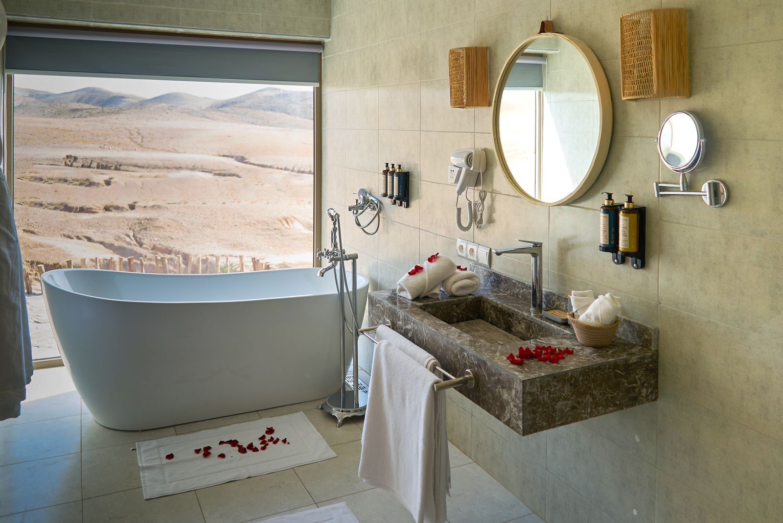 Private bathroom with a freestanding bathtub facing a window onto the desert hills