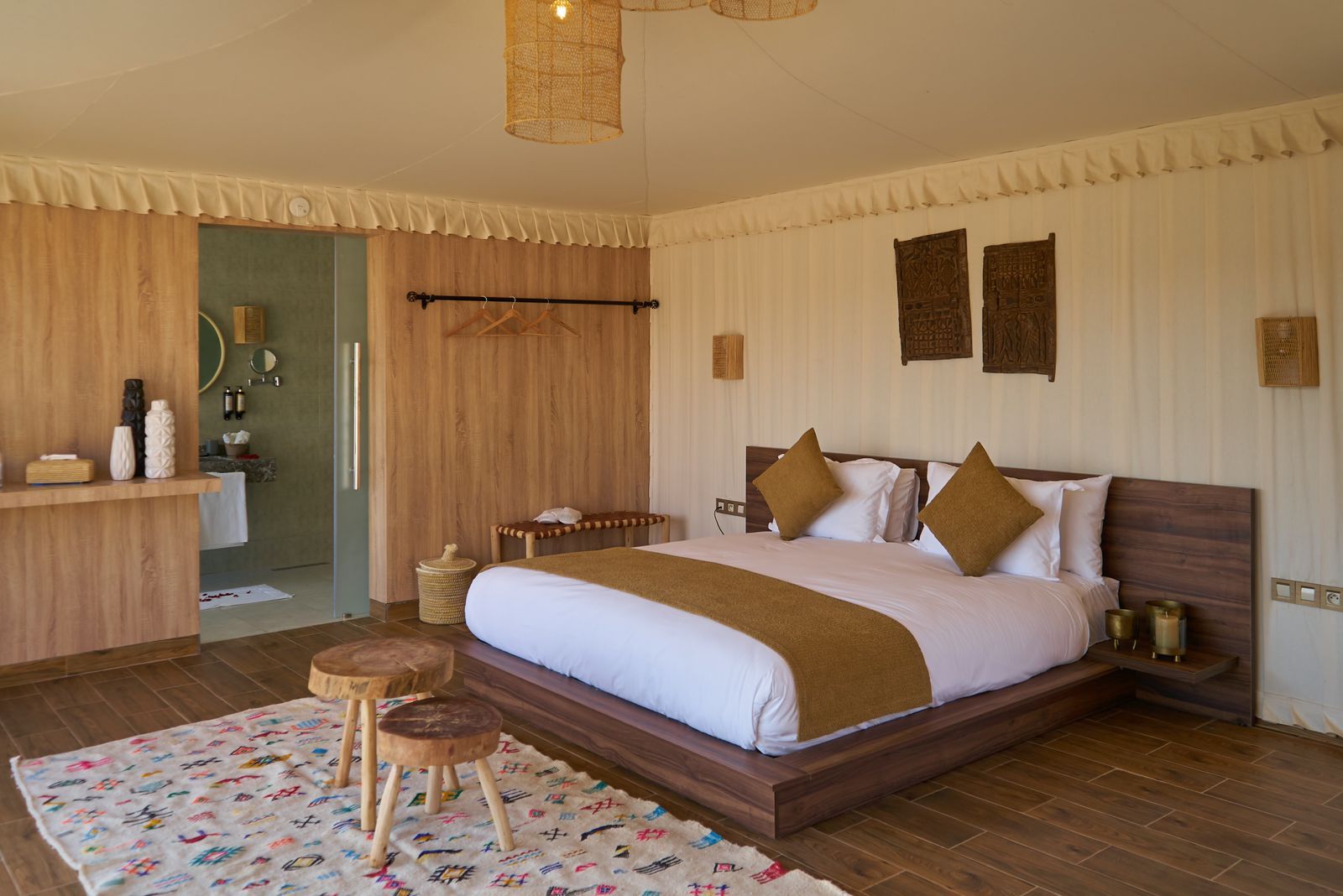Interior of a deluxe tent with a double bed, wooden panelling and a Berber rug