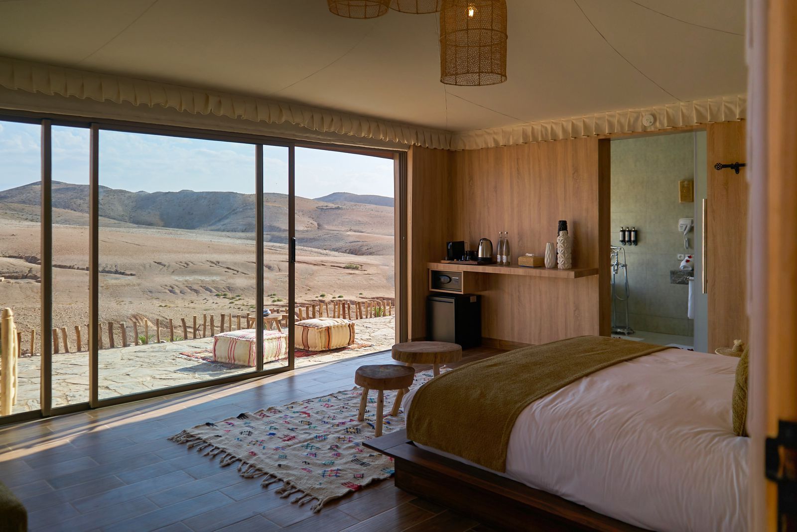 Suite tent with a floor-to-ceiling window opening onto the hills of the Agafay Desert