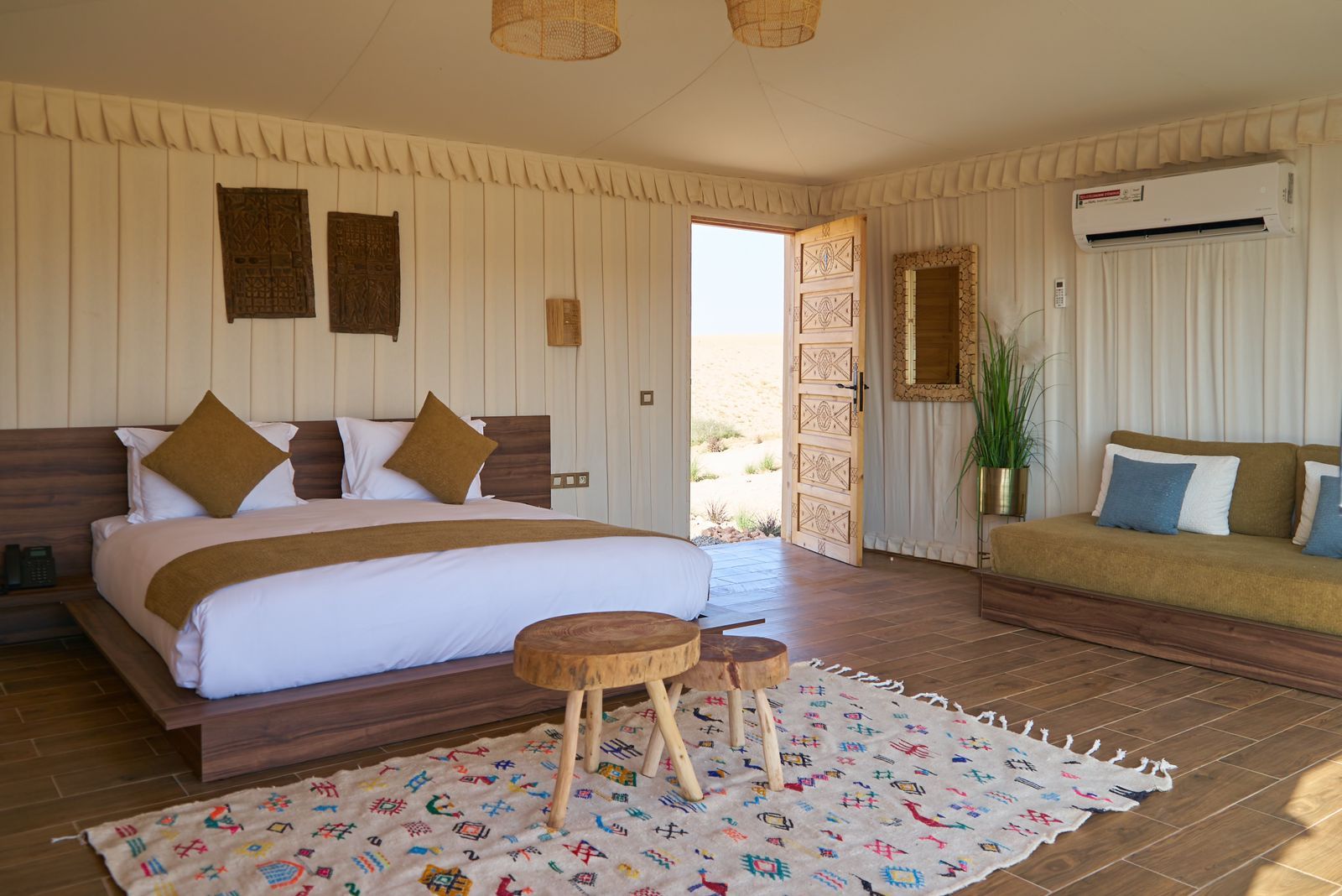 Tent interior opening through a full-height sliding window onto a terrace and the Agafay hills