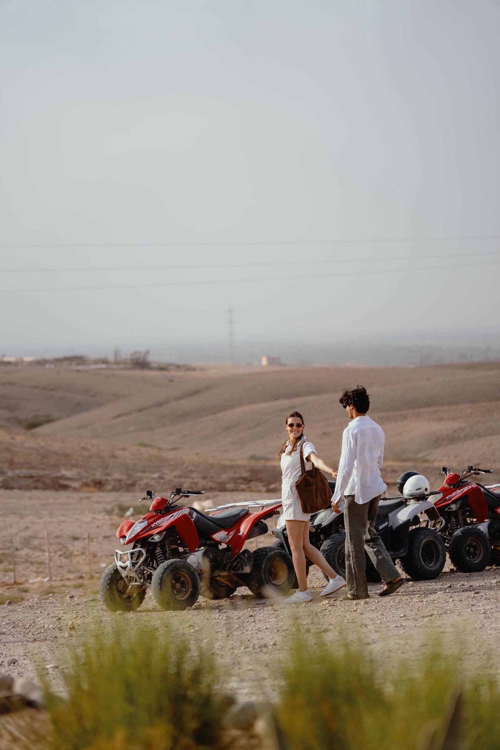 A couple standing beside two parked quads on a track across the Agafay plateau