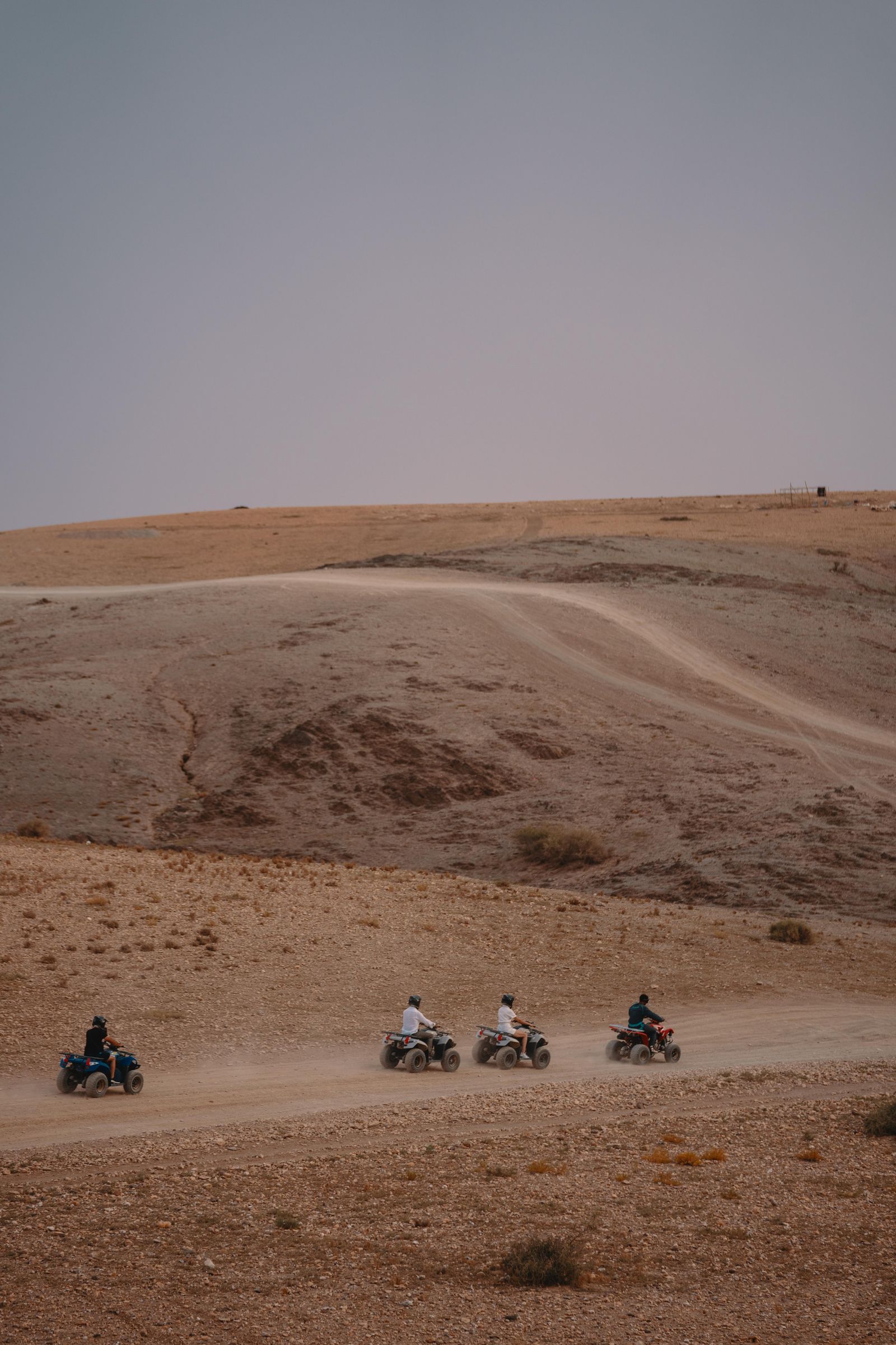Quad bikes strung out along a track cut into the bare hillside of the Agafay plateau