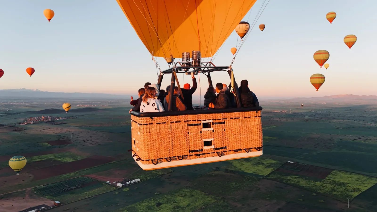 Mongolfiere che si alzano all’alba sulla piana vicino a Marrakech, l’Atlante all’orizzonte